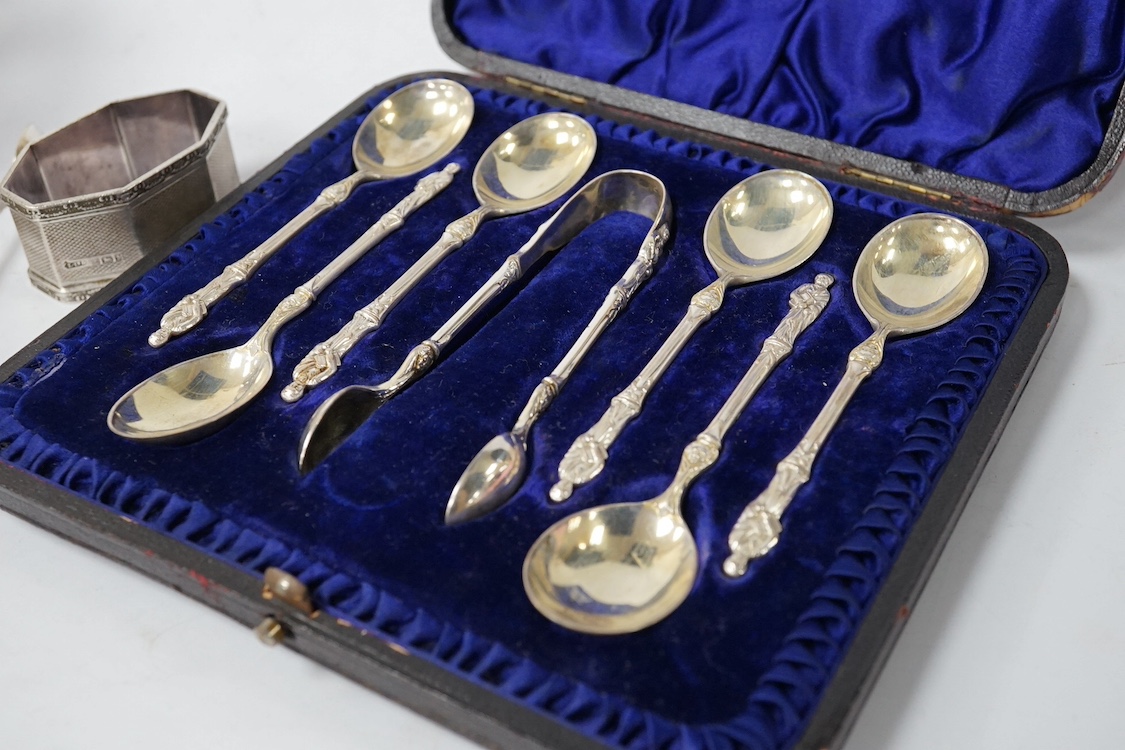 A George V silver mounted brass cased travelling timepiece, London, 1916, 70mm, together with a silver napkin ring, a pair of silver sugar tongs, a cased set of silver Victorian silver teaspoons with sugar tongs and a pl